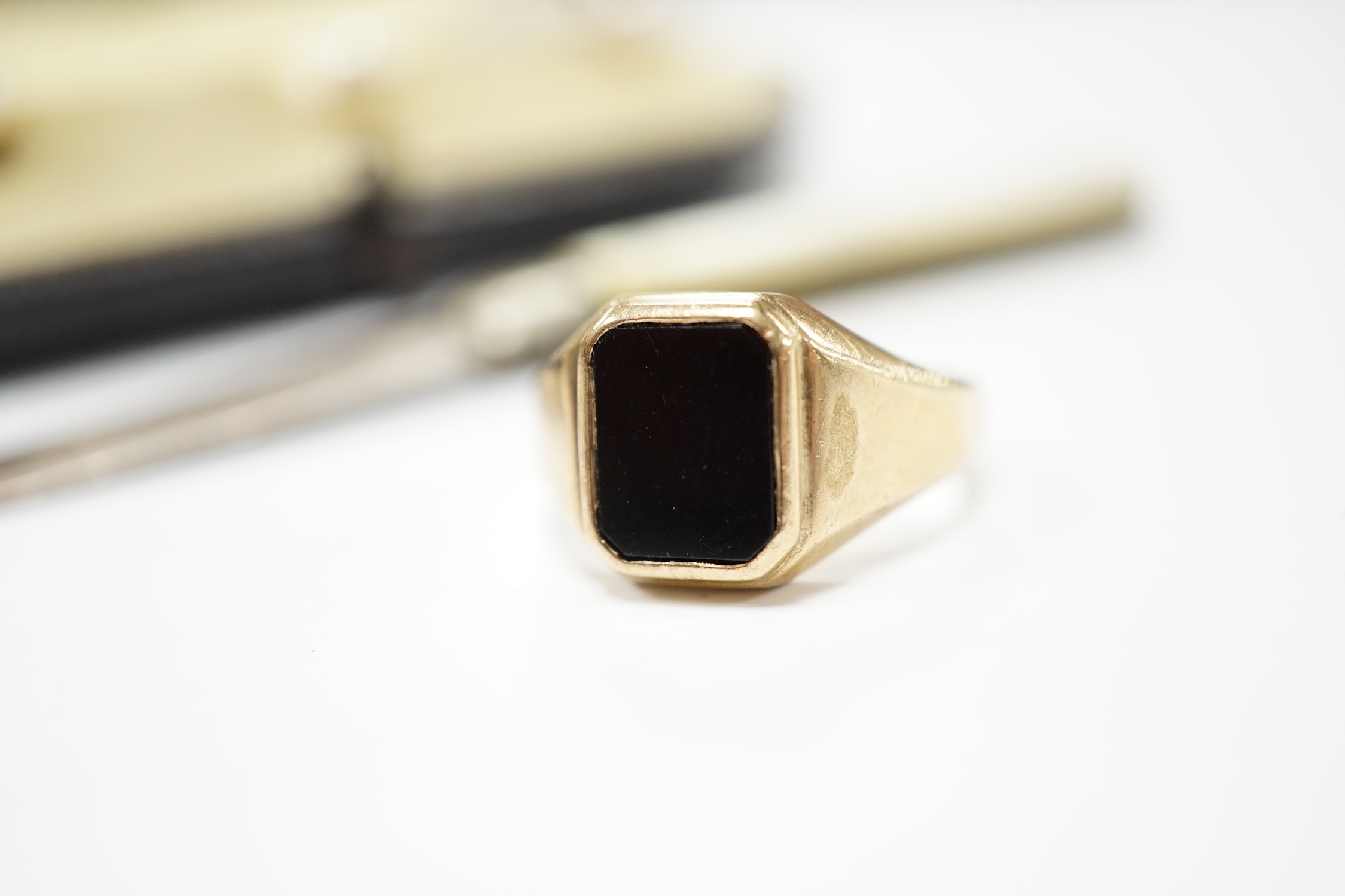 A 1960's 9ct gold and black onyx set signet ring, size O, gross weight 5.1 grams, a cased set of three yellow metal and cultured pearl set dress studs, a 9ct stick pin and a small mother of pearl handled silver fruit kni